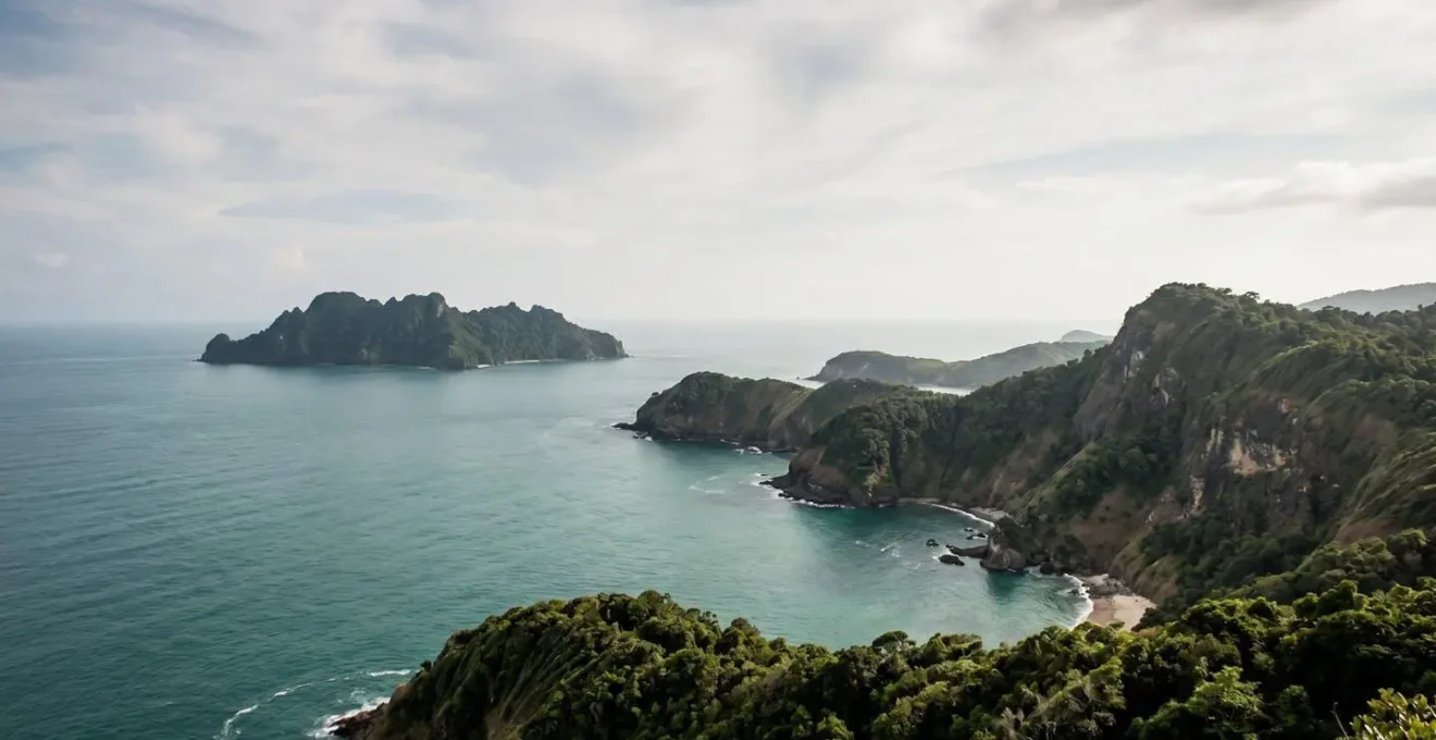 Paysage côtier isolé avec végétation dense et reliefs naturels créant une barrière naturelle d'accès, illustrant les destinations protégées par leur géographie