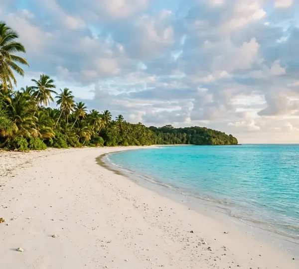 Plage tropicale déserte aux eaux turquoise et sable blanc immaculé bordée de végétation luxuriante, incarnant un paradis terrestre encore préservé du tourisme de masse