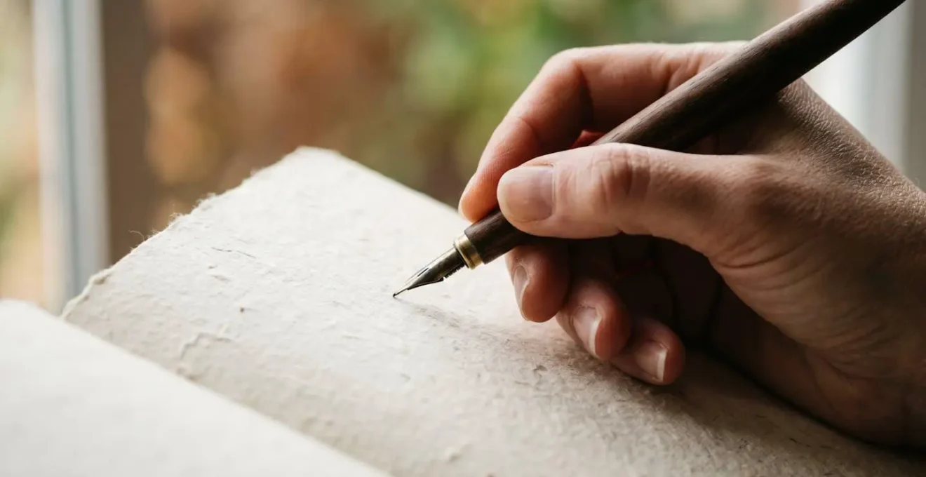 Détail macro d'une main écrivant dans un carnet avec des éléments naturels en arrière-plan flou