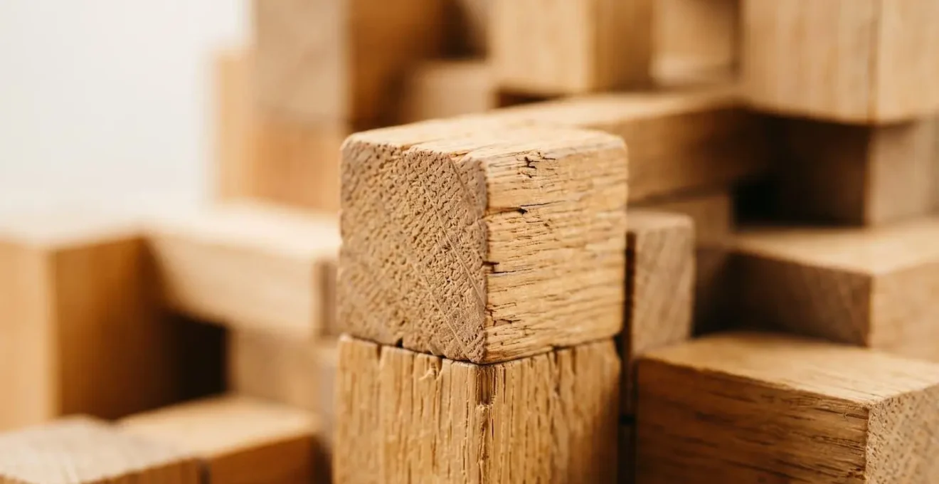 Gros plan macro sur des blocs de bois naturel empilés de manière architecturale, représentant un système modulaire de planification avec textures organiques et ombres douces
