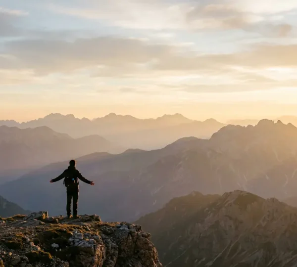 Voyageur contemplant un paysage de montagne au lever du soleil dans une posture méditative